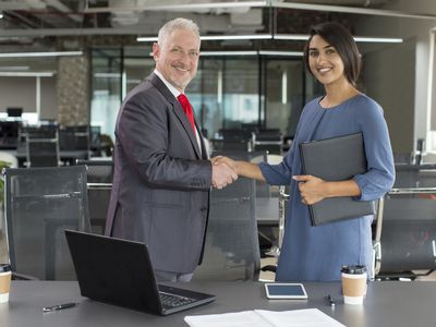 A businessman and a businesswoman shaking hands to close a deal