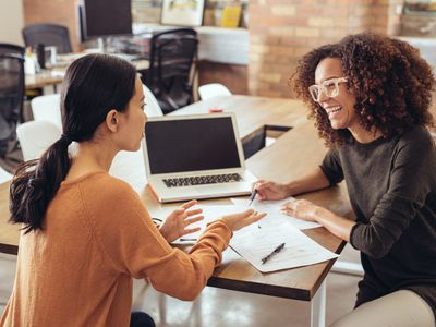 Two women discussing the terms of a book contract.