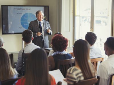 Businessman leading sales training at television screen