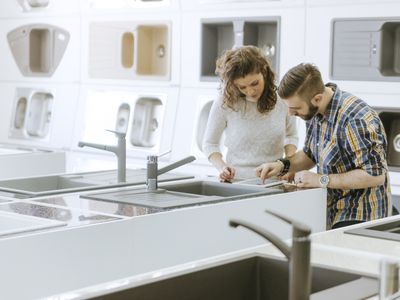 Customers consulting saleswoman in shop for kitchen sinks
