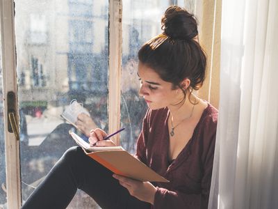 Young woman writing in diary.