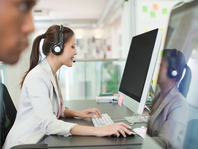 Saleswoman at her desk wearing a headset on the first day of her new job.