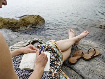 Woman writing in journal on seaside of Italy.