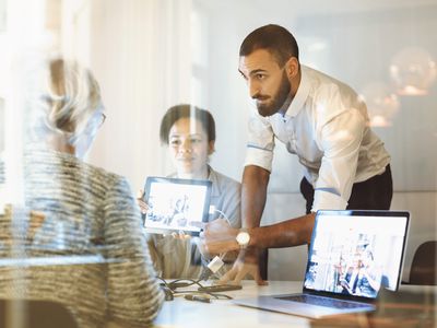 Sales team giving presentation to a client in a glass-walled office