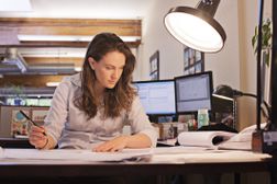 Woman working at her desk, developing a strategy to manage change in a project.