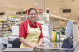 Portrait of smiling woman working at grocery checkout