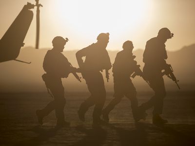 在沙漠景观中直升机附近的士兵轮廓