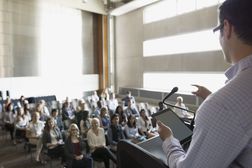 Professor with digital tablet speaking to students auditorium