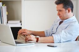 一个沮丧的男人在桌子上带笔记本电脑