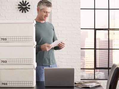 A fed-up lawyer packing up his office with boxes of files and a stack of bills on his desk.