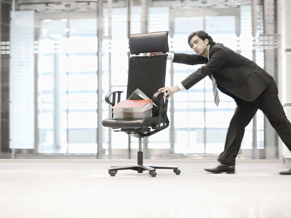 Businessman pushing office chair with supplies