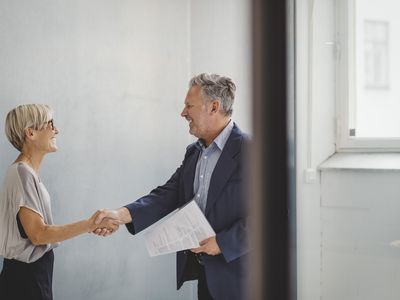 Mature businessman and businesswoman shaking hands in new office