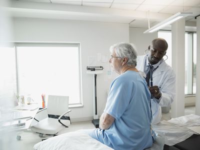 Doctor checking senior mans back in examination room