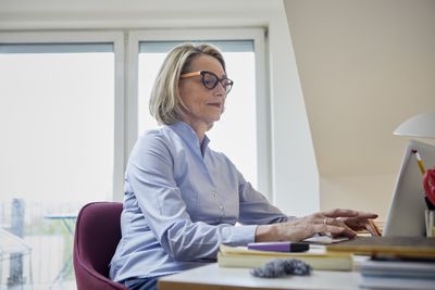 成熟的女人在家办公时使用笔记本电脑